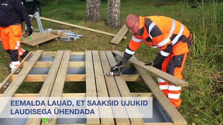 Juhendvideo kaader: töötajad paigaldavad laudist, ekraanil eestikeelne juhis